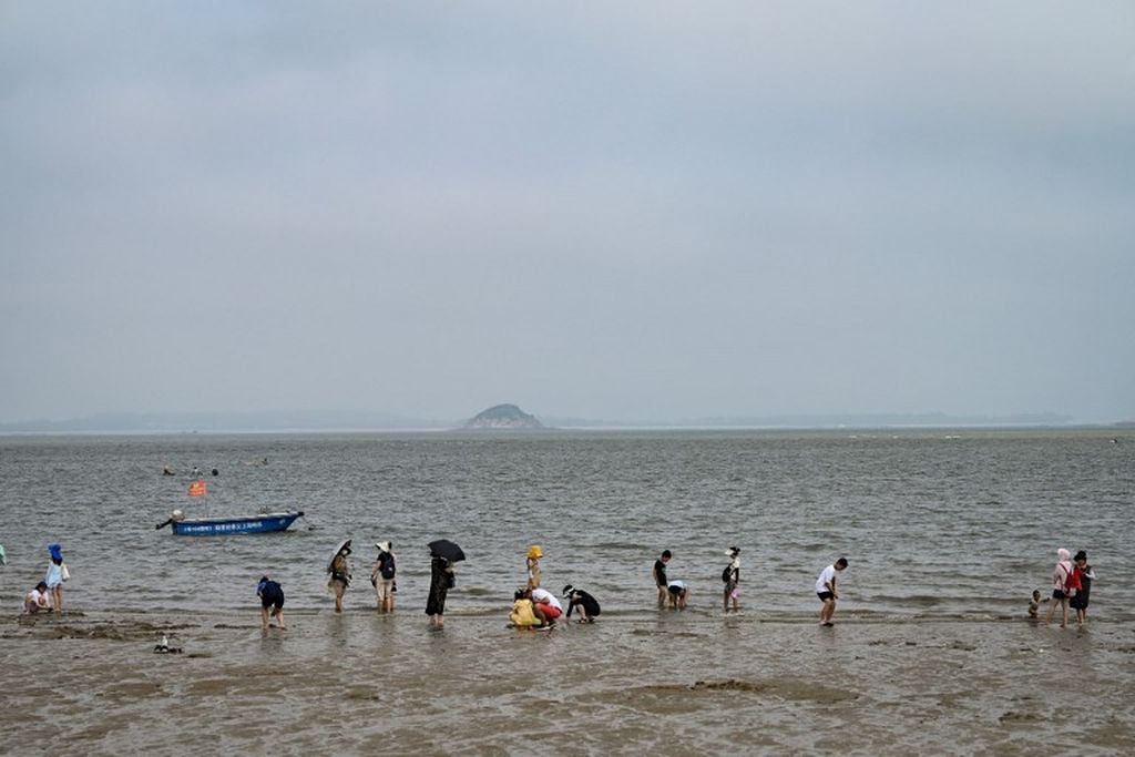 Foto yang diambil pada 25 Juli 2022 ini menunjukkan orang-orang bersantai di pantai di mana Pulau Jinmen, Taiwan, dapat dilihat dari Xiamen, Provinsi Fujian, China selatan. 