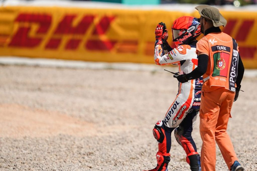 Pebalap tim Repsol Honda, Marc Marquez, dikawal oleh <i>marshal</i> setelah mengalami kecelakaan di mana motornya menabrak pebalap RNF Racing, Miguel Oliveira, di tikungan 3 Sirkuit Internasional Algarve, Portimao, Portugal, dalam balapan pembuka MotoGP 2023, Minggu (26/3/2023).