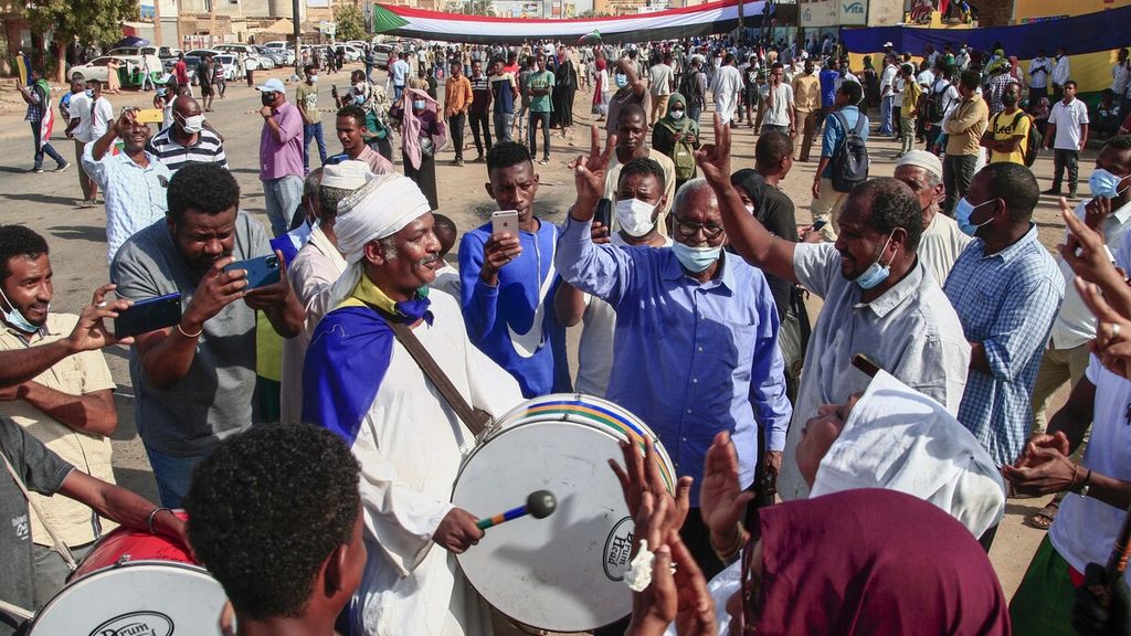 Aksi kesenian dalam unjuk rasa warga Omdurman, Sudan, pada 13 Desember 2021. Mereka meminta percepatan transisi dari kekuasaan militer menjadi pemerintahan sipil yang dipilih oleh rakyat. Sudan dikelola oleh dewan berdaulat pejabat militer dan sipil yang mengawasi periode transisi hingga pemilihan umum pada 2023.