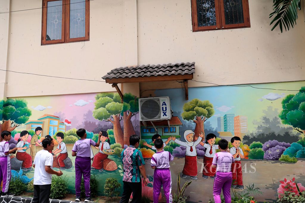 Guru beserta siswanya menyelesaikan mural yang bertema anak-anak sekolah pada salah satu tembok bangunan di SD Candi 1, Kota Semarang, Jawa Tengah, Selasa (1/11/2022).