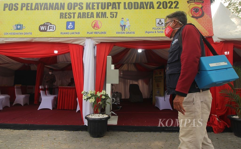 Sulaeman (58), perawat di Puskesmas Purwasari, Kabupaten Karawang, Jawa Barat, membawa termos penyimpan vaksin Covid-19 di <i>rest area</i> atau tempat peristirahatan Kilometer 47 Jalan Tol Jakarta-Cikampek, Minggu (24/4/2022). <i>Rest area</i> itu menyediakan vaksinasi gratis, baik untuk dosis lengkap maupun <i>booster</i>, bagi pemudik.