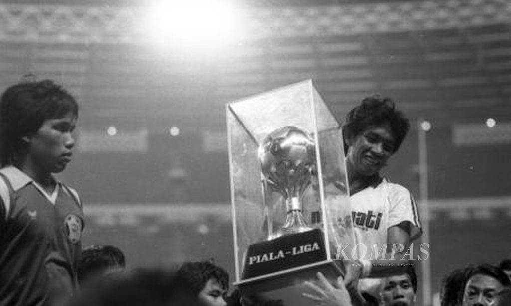 Kapten Makassar Utama Sumirlan, menerima piala dari Administrator Liga, Acub Zainal. Tim Makassar Utama Juara Liga Sepak bola Galatama Indonesia ke-2 tahun 1986 setelah menaklukkan Niac Mitra Surabaya 1-0 di final.