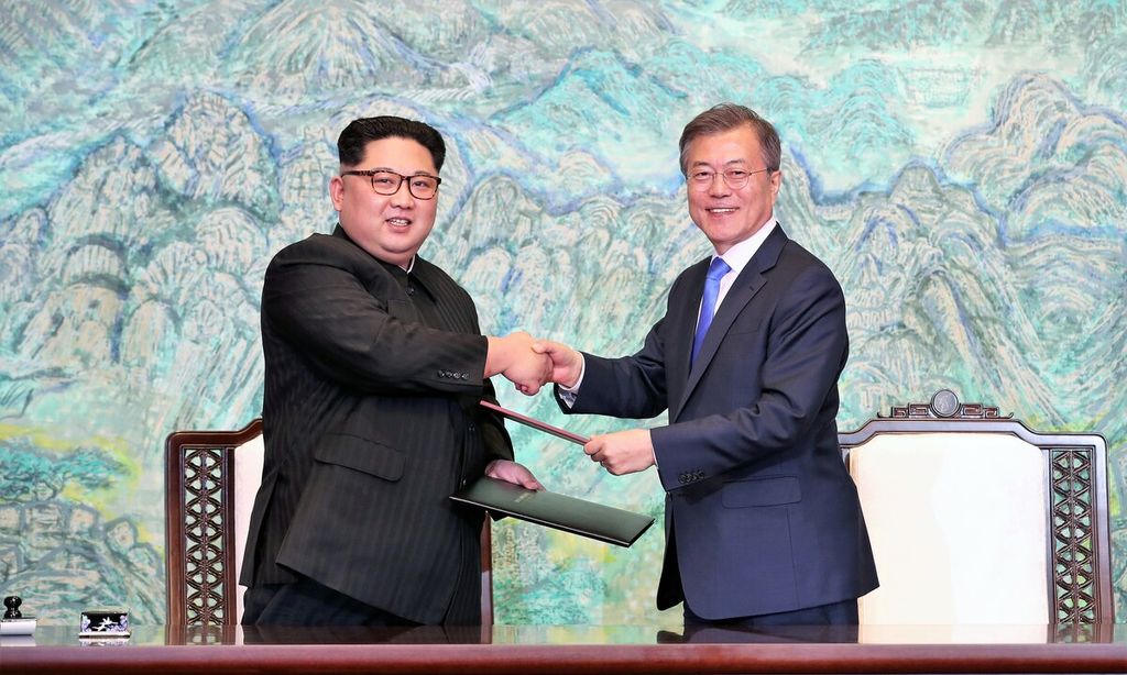 Pemimpin Korea Utara Kim Jong Un (kiri) dan Presiden Korea Selatan Moon Jae-in (kanan) saling bertukar dokumen dalam pertemuan di Panmunjom, Jumat (27/4/2018).