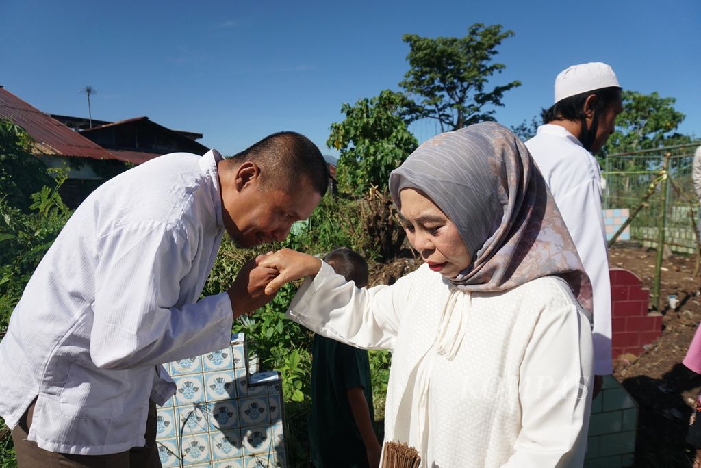 Warga yang beragama Islam saling berjabat dan mencium tangan ketika berziarah ke kompleks Makam Sekar Kedaton di Manado, Sulawesi Utara, selepas shalat Id pada Idul Fitri 1443 Hijriah, Senin (2/5/2022). Sebagian warga menilai perayaan Lebaran tahun ini lebih semarak karena pembatasan sosial tak lagi ketat seperti dua tahun yang telah lalu.