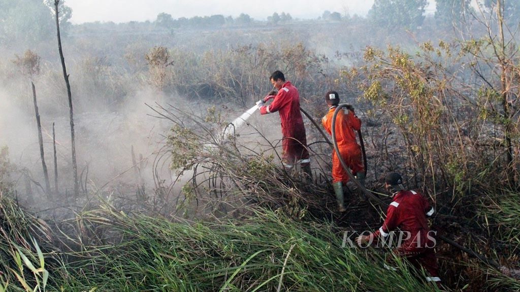 Officials from the Regional Disaster Management Agency in Ogan Ilir, South Sumatra, sprayed water onto the burning land in the district on August 6, 2019.