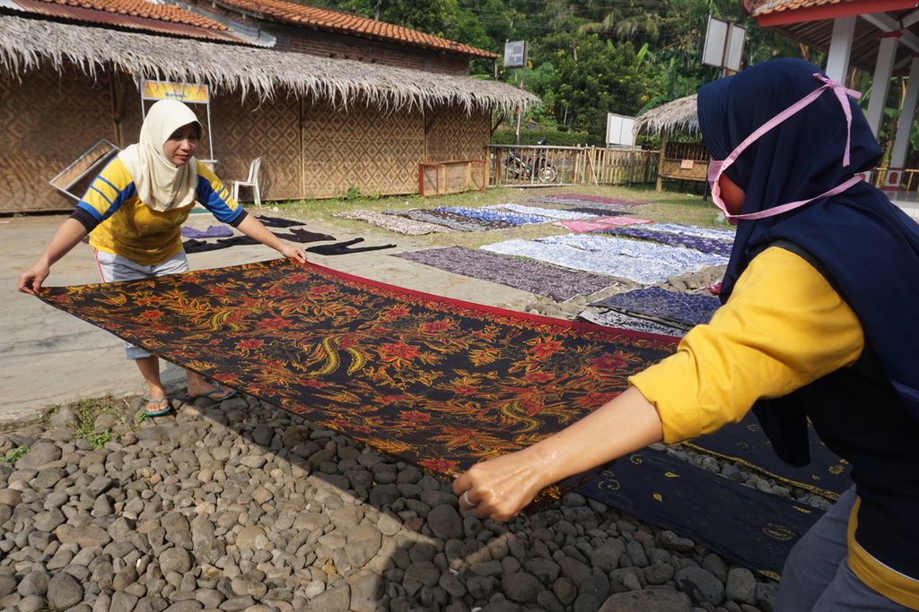 Perajin batik tulis menjemur belasan kain batik tulis di atas batu dan rumput di Desa Papringan, Banyumas, Jawa Tengah, Kamis (6/8/2020).