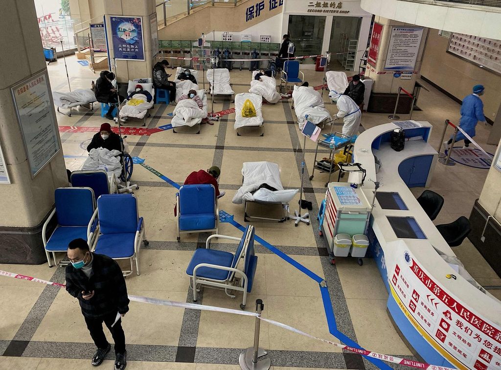 Seorang pria berdiri di depan area yang diberi pembatas, tempat para pasien Covid-19 dibaringkan di  bangsal-bangsal di sebuah lobi rumah sakit di Chongqing, China barat daya, 23 Desember 2022. 