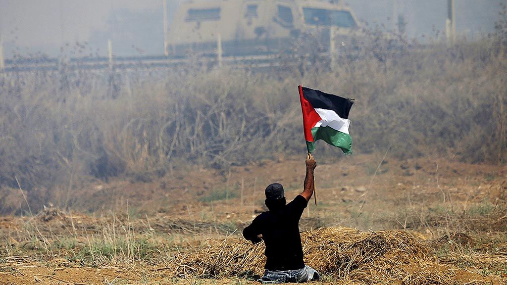 Ibrahim Abu Thuraya,  warga Palestina yang tewas diterjang peluru sniper Israel, Jumat (15/12),  mengibarkan bendera Palestina saat berunjuk rasa menentang pendudukan Israel di dekat perbatasan timur Kota Gaza,   dalam foto dokumentasi bertanggal 19 Mei 2017. 