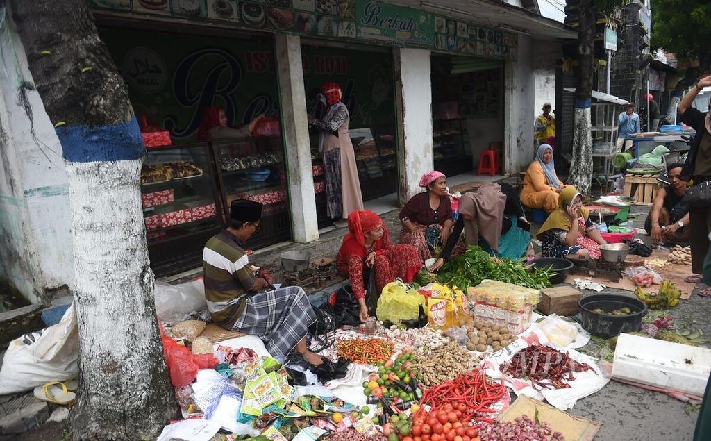 Pedagang Pasar Srimangunan berjualn di pinggir Jalan Panglima Sudirman akibat pasar berlumpur pascabanjir, Kecamatan Sampang, Kabupaten Sampang, Jawa Timur, Senin (2/1/2023). 