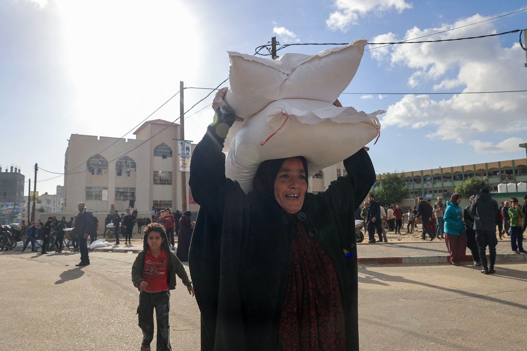 Warga Palestina menerima sekantong tepung di pusat distribusi Badan Bantuan dan Pekerjaan PBB untuk Pengungsi Palestina (UNRWA) di kamp pengungsi Rafah di Jalur Gaza selatan di tengah pertempuran yang sedang berlangsung antara Israel dan gerakan Hamas Palestina, Selasa (21/11/2023).