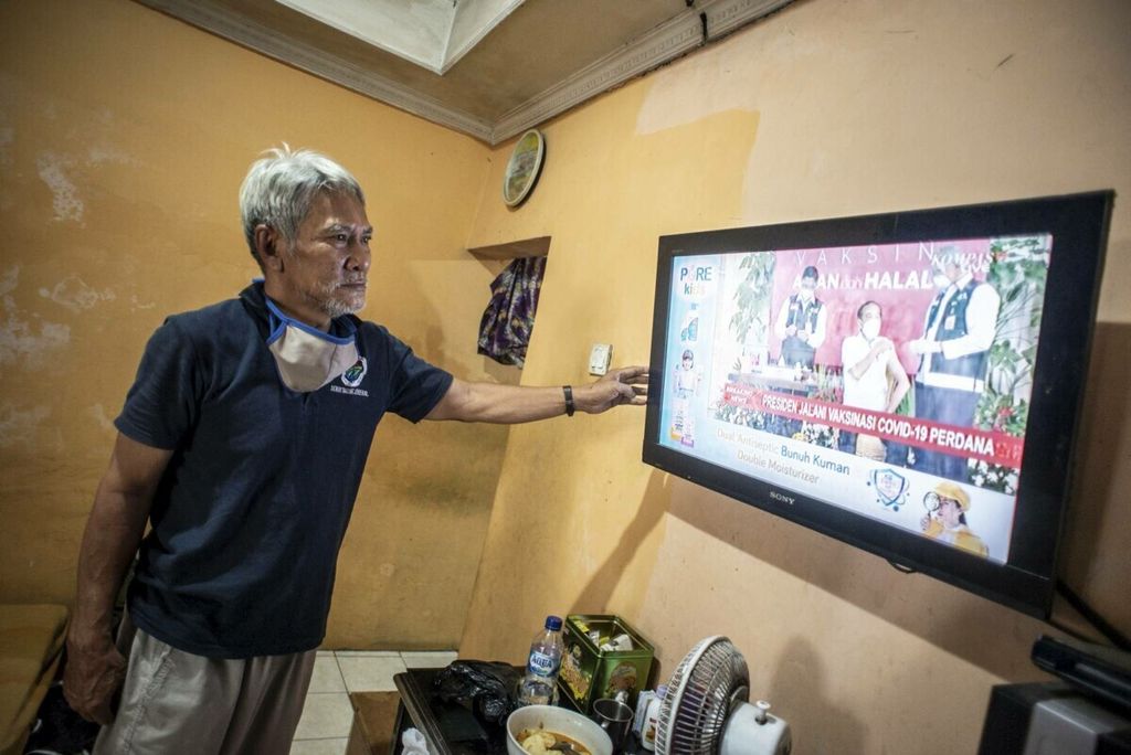 Warga menonton televisi yang menayangkan langsung penyuntikan vaksin CoronaVac perdana di Jakarta, Rabu (13/1/2021). 
