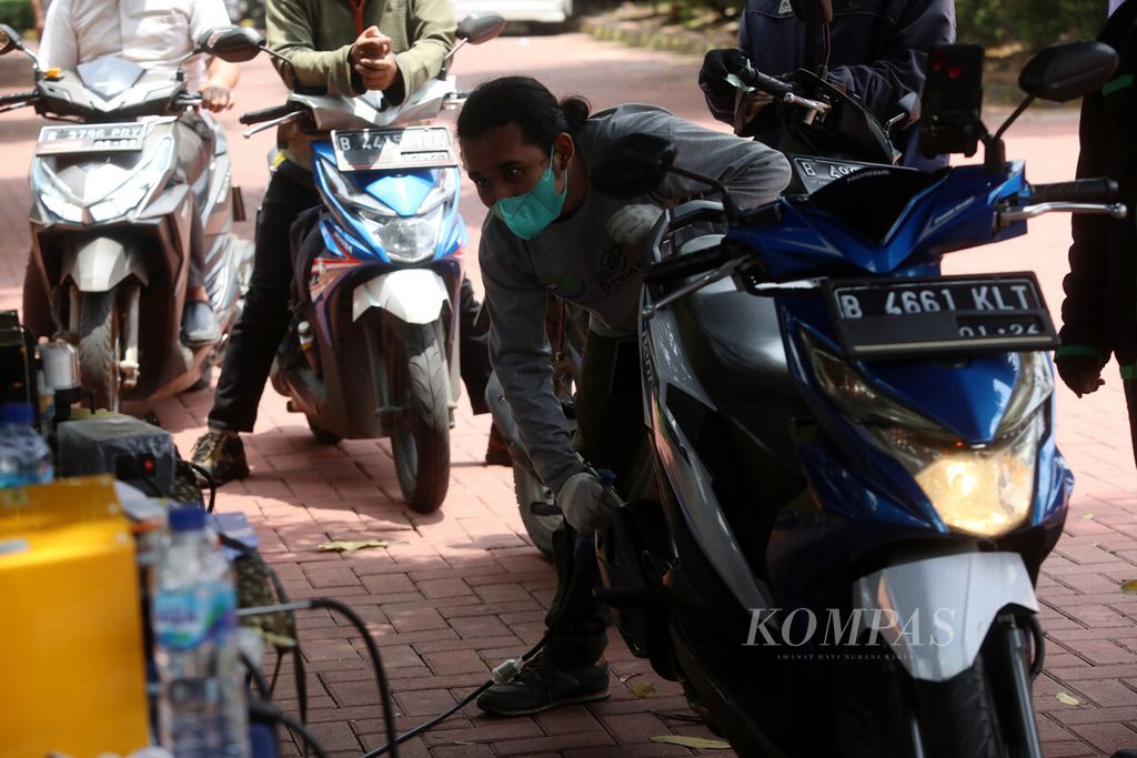 Petugas memasukkan alat penguji emisi ke knalpot sepeda motor saat berlangsung uji emisi gratis di halaman GOR Senam DKI Raden Inten, Jakarta Timur, Selasa (29/3/2022).   