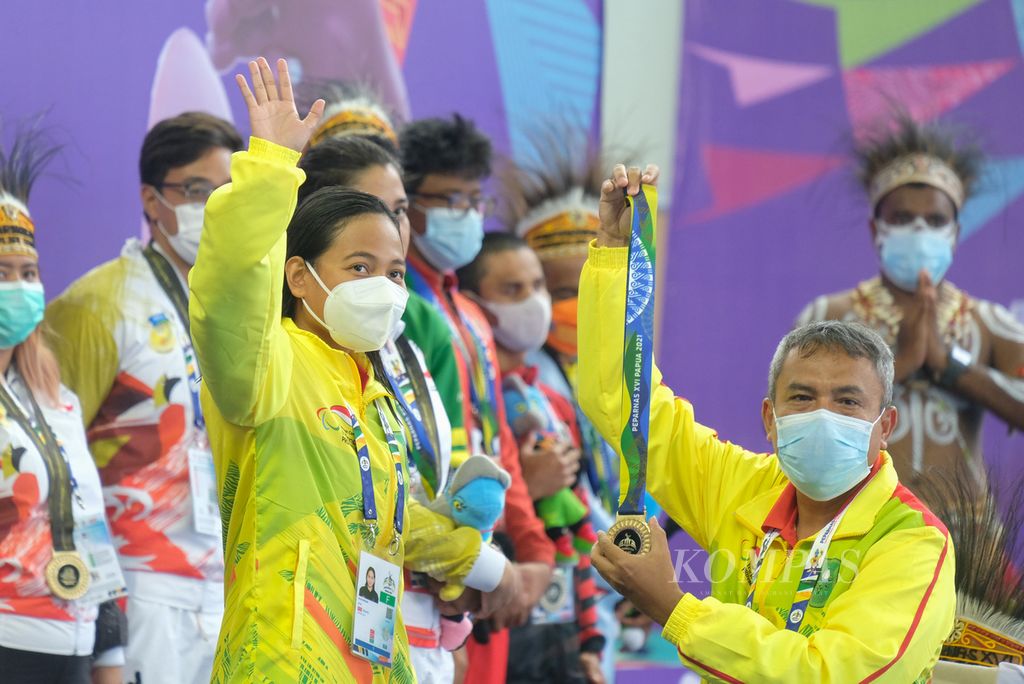 Perenang tunagrahita nasional asal Riau, Syuci Indriani, melambaikan tangan sebelum menerima medali emas nomor 200 meter gaya bebas klasifikasi S14 di Arena Akuatik Lukas Enembe, pada Kamis (11/11/2021). Syuci berhasil mempertahankan raihan emas beruntun dalam tiga ajang Peparnas. 
