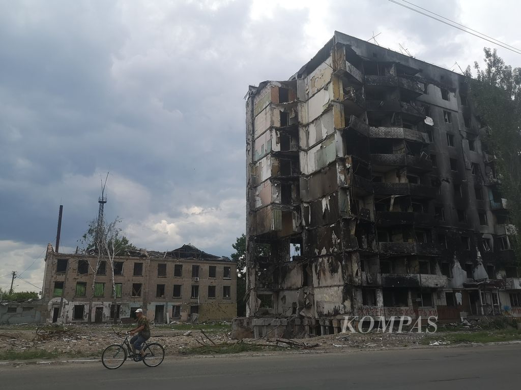 Warga bersepeda melintasi sisa reruntuhan bangunan apartemen yang hancur dihantam rudal Rusia di Borodyanka, sekitar 60 kilometer barat laut Kota Kyiv, Provinsi Kyiv, Ukraina, Jumat (17/6/2022). 