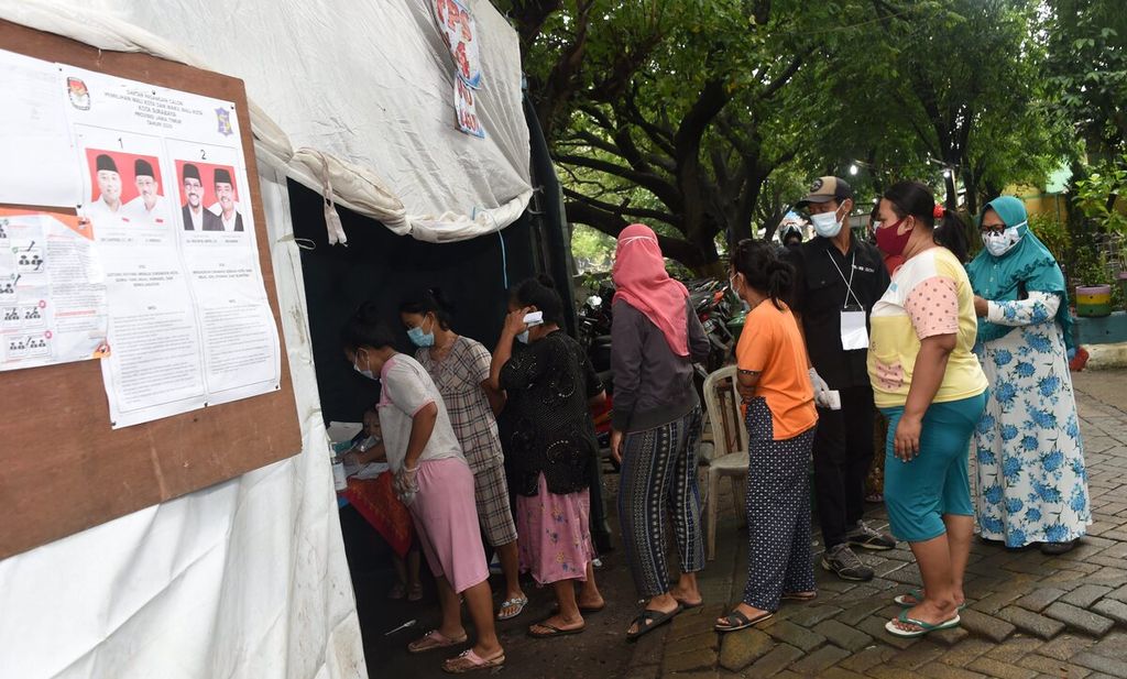 Warga antre untuk menggunakan hak suaranya dalam pemilihan Wali Kota Surabaya di TPS14 yang dibangun di kawasan pemakaman Rangkah, Kelurahan Tambakrejo, Kecamatan Simokerto, Surabaya, Jawa Timur, Rabu (9/12/2020). 