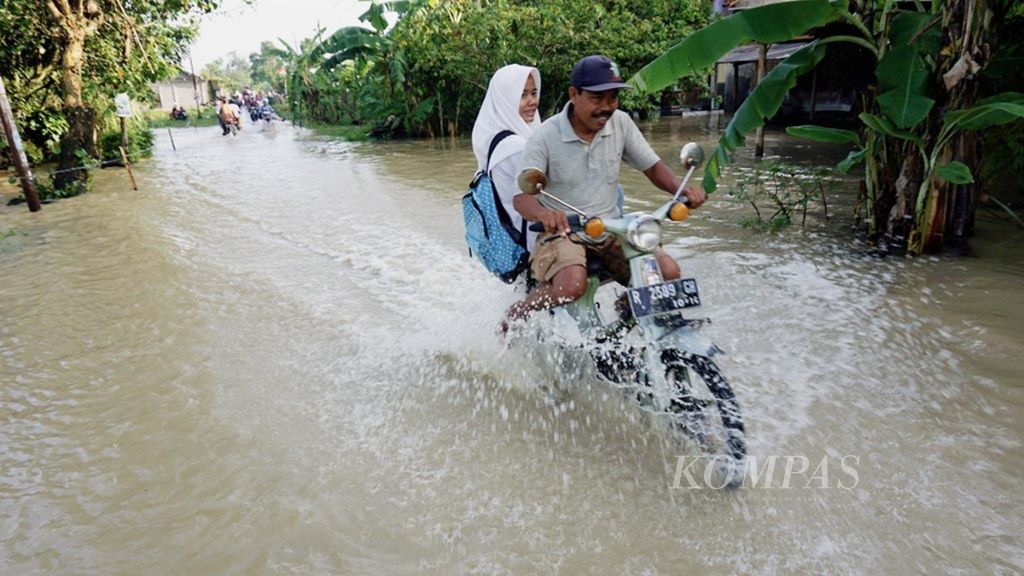 Warga melintasi banjir di Desa Kalisabuk, Kecamatan Kesugihan, Cilacap, Jawa Tengah, pada Selasa (31/10/2017). 