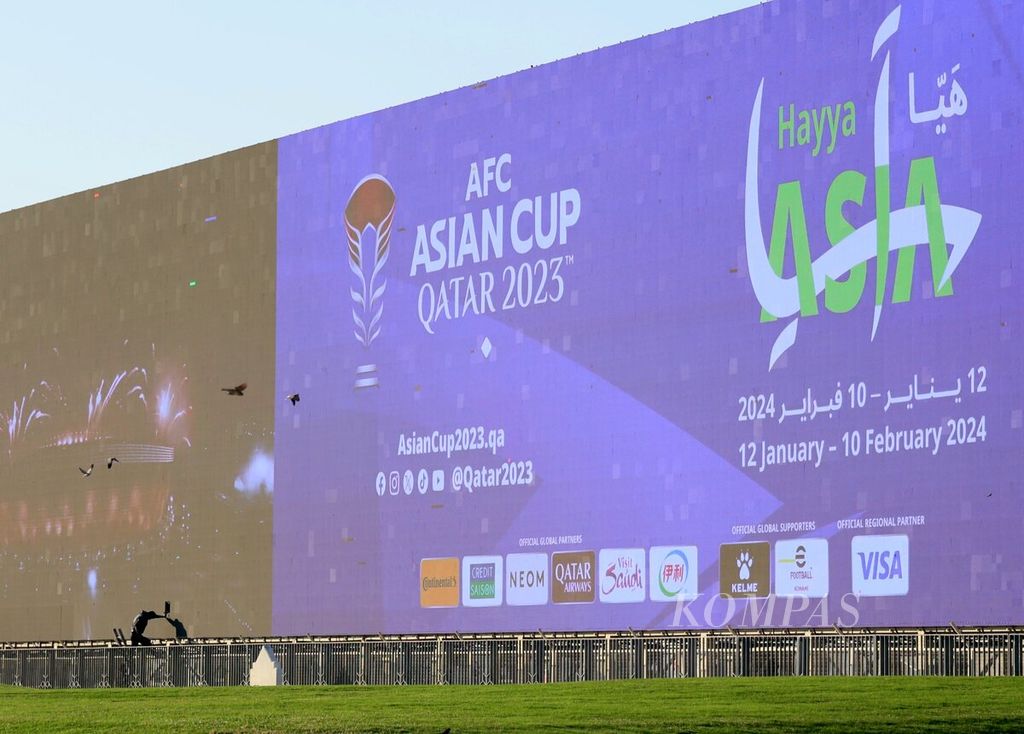 Pekerja memperbaiki layar videotron raksasa yang menampilkan informasi Piala Asia 2024 di sudut kota Doha, Qatar, Rabu (10/1/2024). 