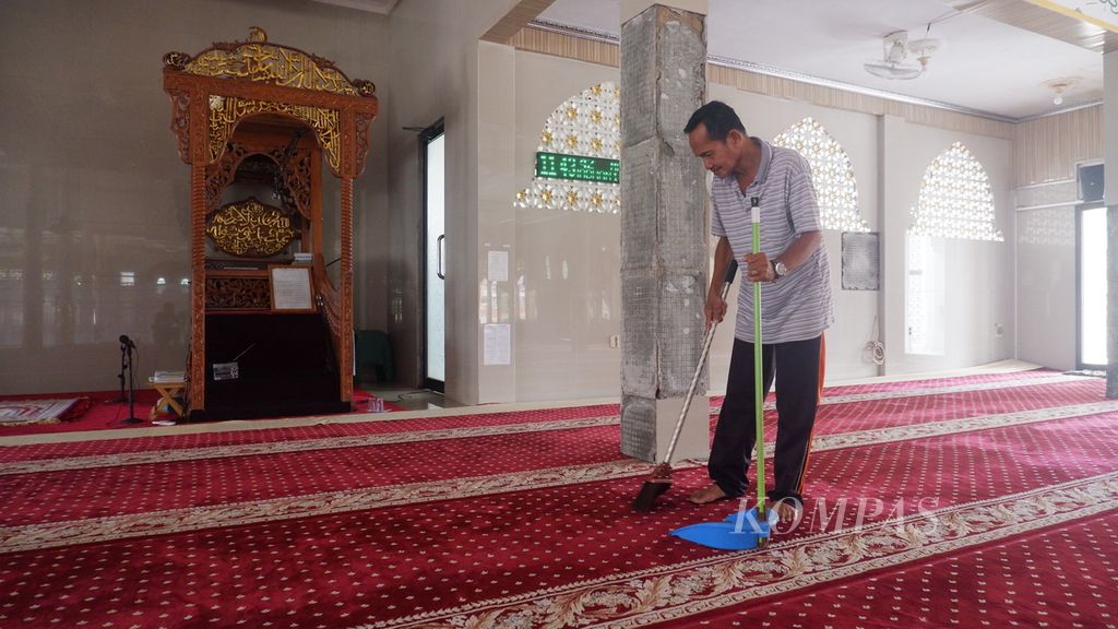 Suriansyah (57), marbot atau kaum masjid, menyapu karpet di Masjid Al-Amin, Banua Anyar, Banjarmasin, Kalimantan Selatan, Kamis (21/3/2024).