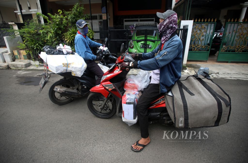 Kurir ekspedisi bertemu dengan sesama rekannya saat dalam perjalanan mengantarkan barang ke pelanggan di kompleks perumahan di kawasan Duren Sawit, Jakarta, Selasa (5/4/2022). Kurir mengambil barang yang didistribusikan dari gudang ke titik <i>base camp </i>dan diantar ke alamat pelanggan. 