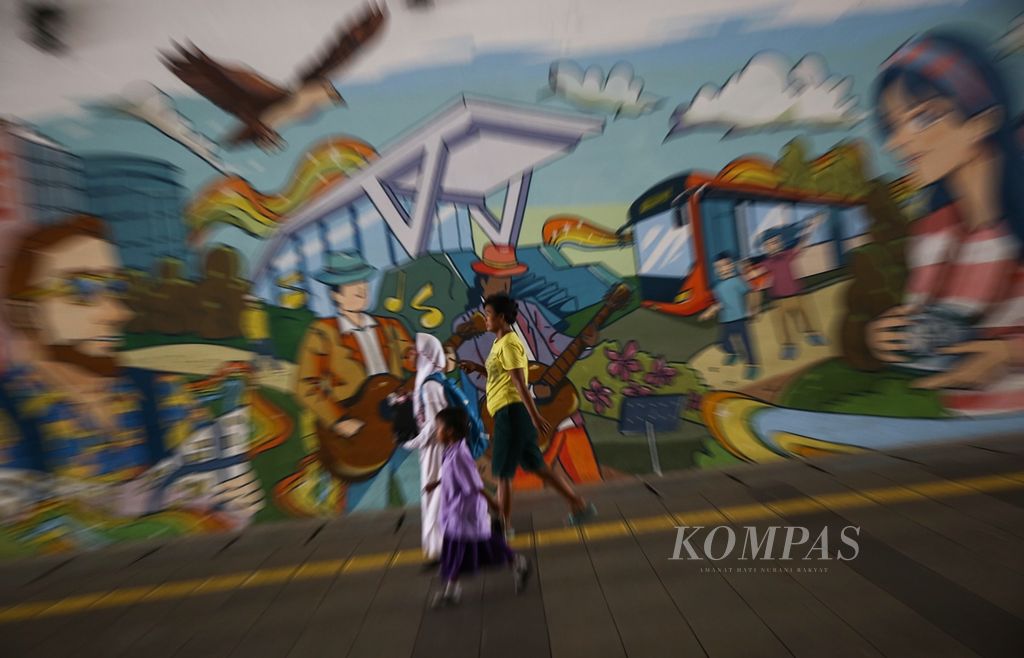 Warga menggunakan ponsel pintarnya saat melintas di terowongan bagi pejalan kaki di Jalan Kendal, Jakarta Pusat, Senin (23/9/2019).