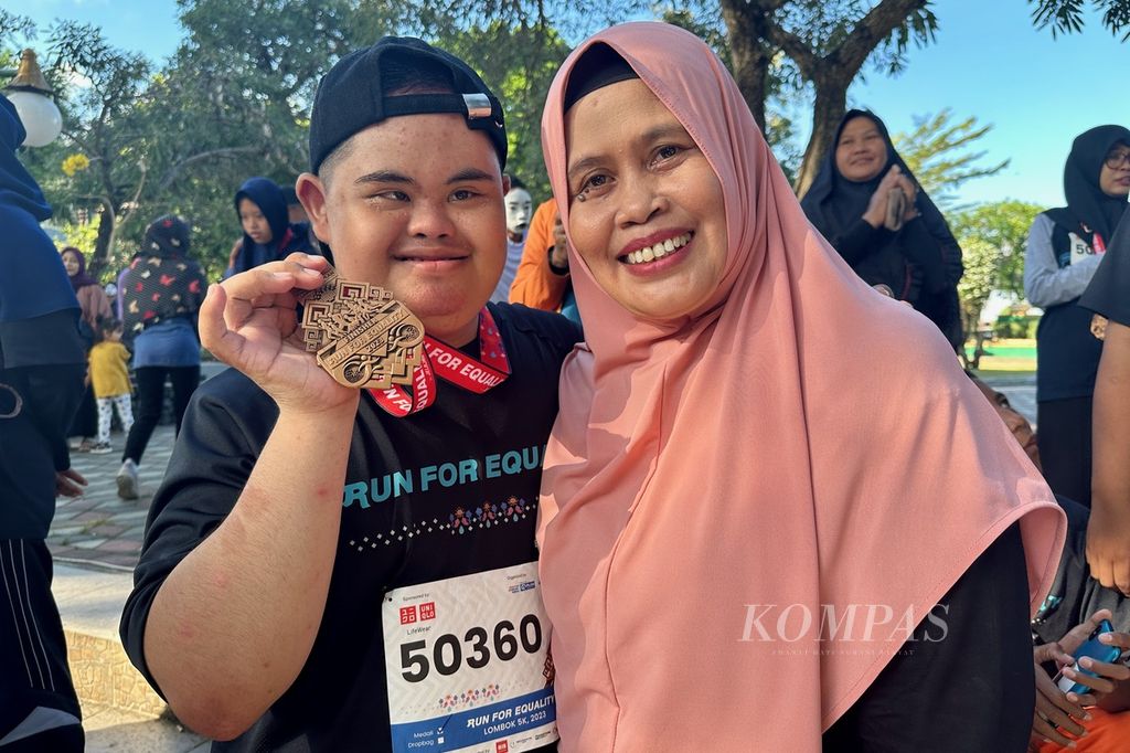 Sri Rahayu (55) bersama putranya, Hisyam Nafis Nurachman (17), menunjukkan medali yang dia dapat setelah mengikuti lari dan jalan gembira bersama "Run For Equality" di Mataram, Nusa Tenggara Barat, Minggu (30/7/2023) pagi.