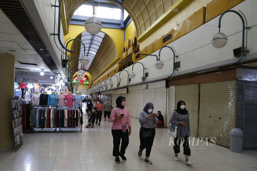 Warga melintasi kios-kios yang mayoritas telah tutup di sepanjang lorong Mal Blok M, Jakarta Selatan, Minggu (29/1/2023). Walaupun pandemi bertahap berubah menjadi endemi, pusat perbelanjaan yang sempat terkenal di awal tahun 2000-an ini saat ini seperti mati suri.