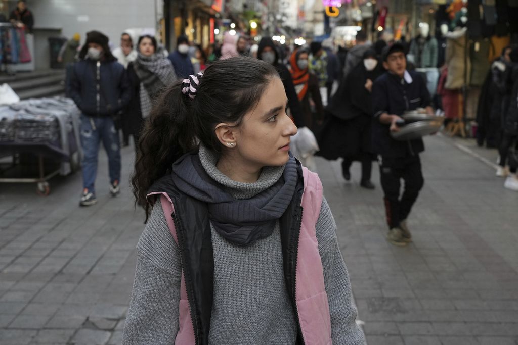 Seorang perempuan berjalan di kawasan pusat bisnis tanpa mengenakan jilbab wajibnya di pusat kota Teheran, Iran, Jumat (23/12/2022). Iran dilanda unjuk rasa nasional sejak September 2022 setelah kematian perempuan muda saat ditahan polisi karena diduga tidak mematuhi kewajiban mengenakan jilbab. 