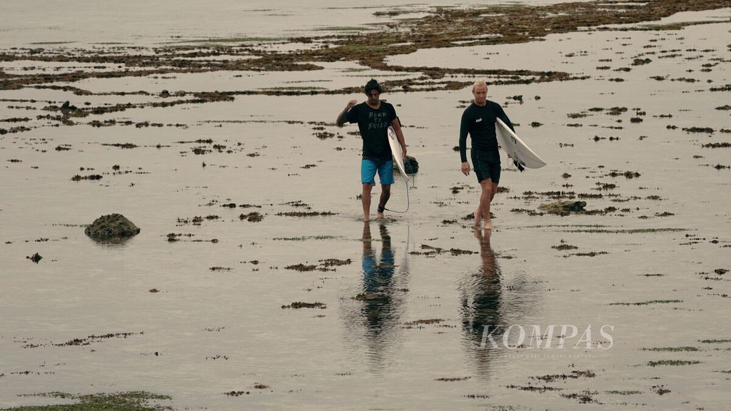 Peselancar berjalan di pantai seusai berlatih menjelang Liga Selancar Dunia (World Surf League) di Pantai Plengkung alias G-Land di Taman Nasional Alas Purwo, Banyuwangi, Jawa Timur, Kamis (26/5/2022).