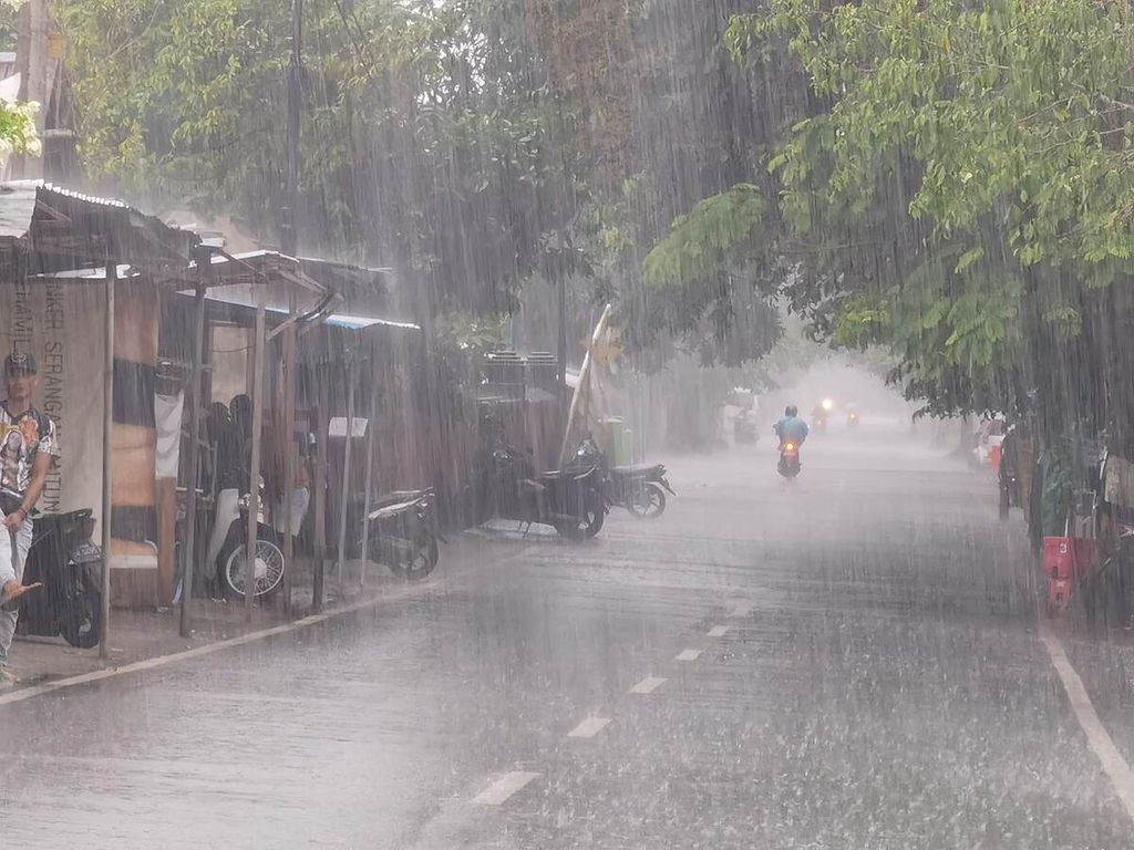 Pengguna jalan melintas saat hujan deras melanda Kota Mataram, Nusa Tenggara Barat, Februari 2021 .