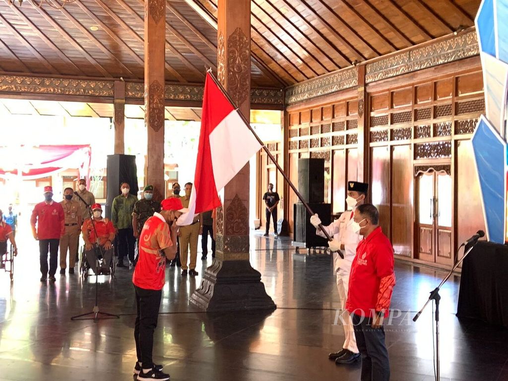Atlet bulu tangkis Paralimpiade Indonesia, Suryo Nugroho (kiri), mencium bendera Merah Putih saat acara pengukuhan kontingen Indonesia untuk ASEAN Para Games 2022 di Balai Kota Surakarta, Senin (25/7/2022). Indonesia menargetkan gelar juara umum dengan meraih minimal 104 medali emas pada ajang itu. 