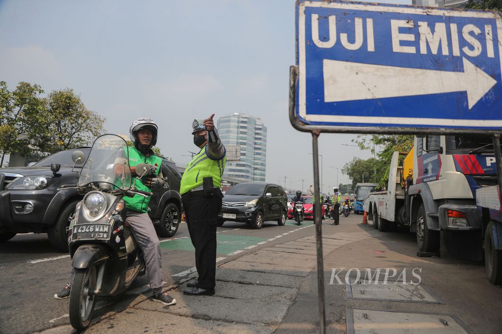 Polisi menunjukkan tempat uji emisi kepada pengendara ojek daring di Jalan Letjen MT Haryono, Jakarta Selatan, Jumat (1/9/2023). Bagi motor yang tidak lolos uji emisi akan dikenakan denda tilang Rp 250.000 dan untuk mobil Rp 500.000.