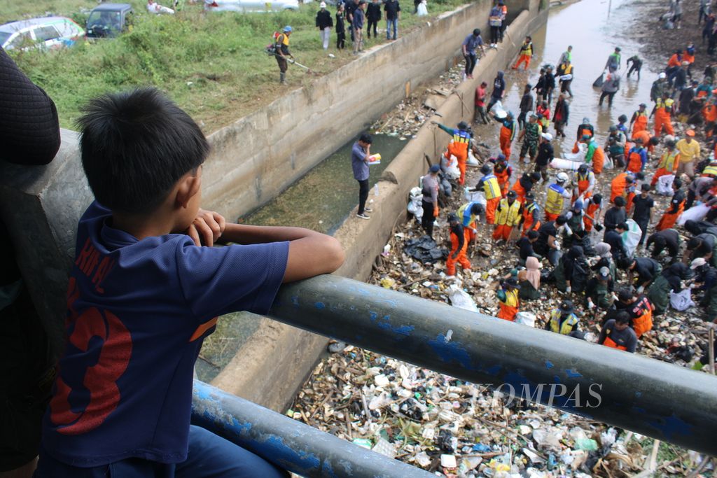 Warga mengamati relawan dan petugas gabungan membersihkan badan Sungai Cikeruh di Bendungan Bugel, Kecamatan Cileunyi, Kabupaten Bandung, Jawa Barat, Rabu (26/7/2023).