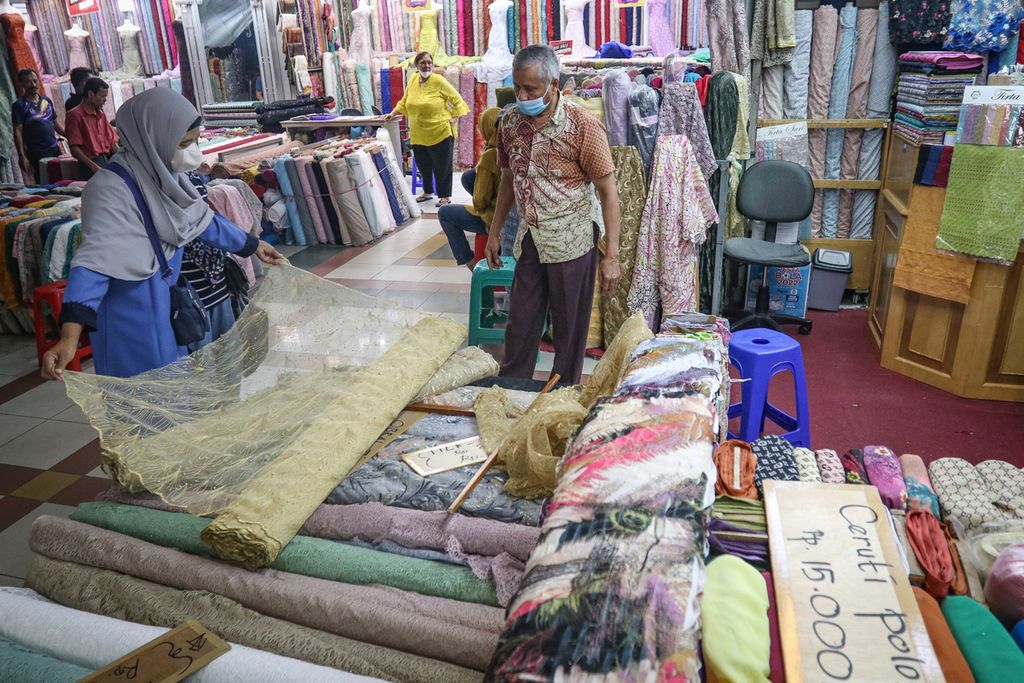 Pengunjung memeriksa kain yang akan dibeli di toko tekstil di Pasar Tanah Abang Blok B, Jakarta Pusat, Desember 2022. Tekstil Indonesia tertekan akibat derasnya impor pakaian bekas.