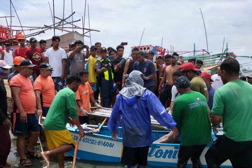Foto selebaran yang diambil pada 3 Oktober 2023 dan dirilis Penjaga Pantai Filipina pada 4 Oktober 2023 menunjukkan aparat mengambil jenazah nelayan yang tewas akibat kapalnya ditabrak kapal komersial asing tak dikenal di Laut China Selatan.  