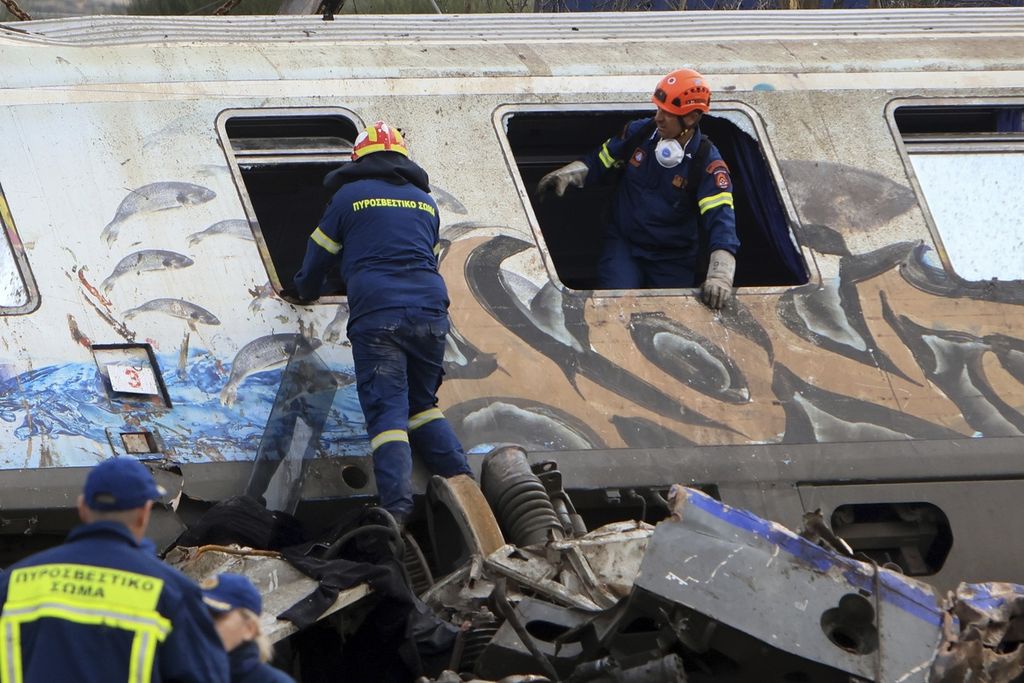 Tim penyelamat berusaha mengevakuasi korban dari salah satu gerbong yang terbakar setelah tabrakan maut antara kereta penumpang dan kereta barang di Tempe, dekat Kota Larissa, Yunani, Rabu (1/3/2023). Puluhan penumpang tewas dalam kejadian itu. 