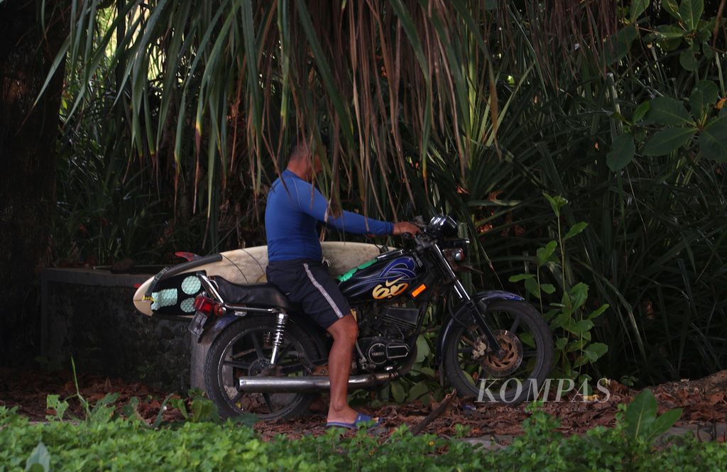 Seorang laki-laki memarkirkan motornya saat hendak bermain selancar ombak di Pantai Cimaja, Kabupaten Sukabumi, Jabar, Rabu (24/5/2023). Pantai Cimaja memiliki ombak besar dan khas yang cocok untuk olahraga selancar ombak. 