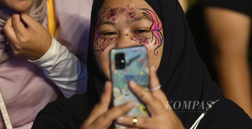 Pengunjung berswafoto setelah wajahnya dilukis dalam hari kedua Joyland Festival 2022 yang berlangsung di Stadion Softball Gelora Bung Karno, Jakarta, Sabtu (5/11/2022). 