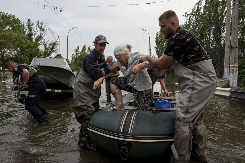 Petugas penyelamat mengevakuasi seorang perempuan tua dari banjir di Kherson, Ukraina, Rabu (7/6/2023).