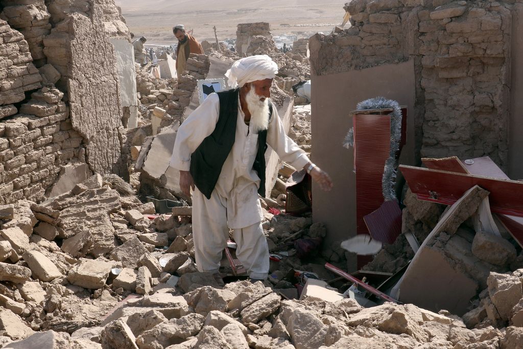 Seorang pria membersihkan rumah setelah gempa bumi di Distrik Zenda Jan di Provinsi Herat, Afghanistan barat, Minggu (8/10/2023). 