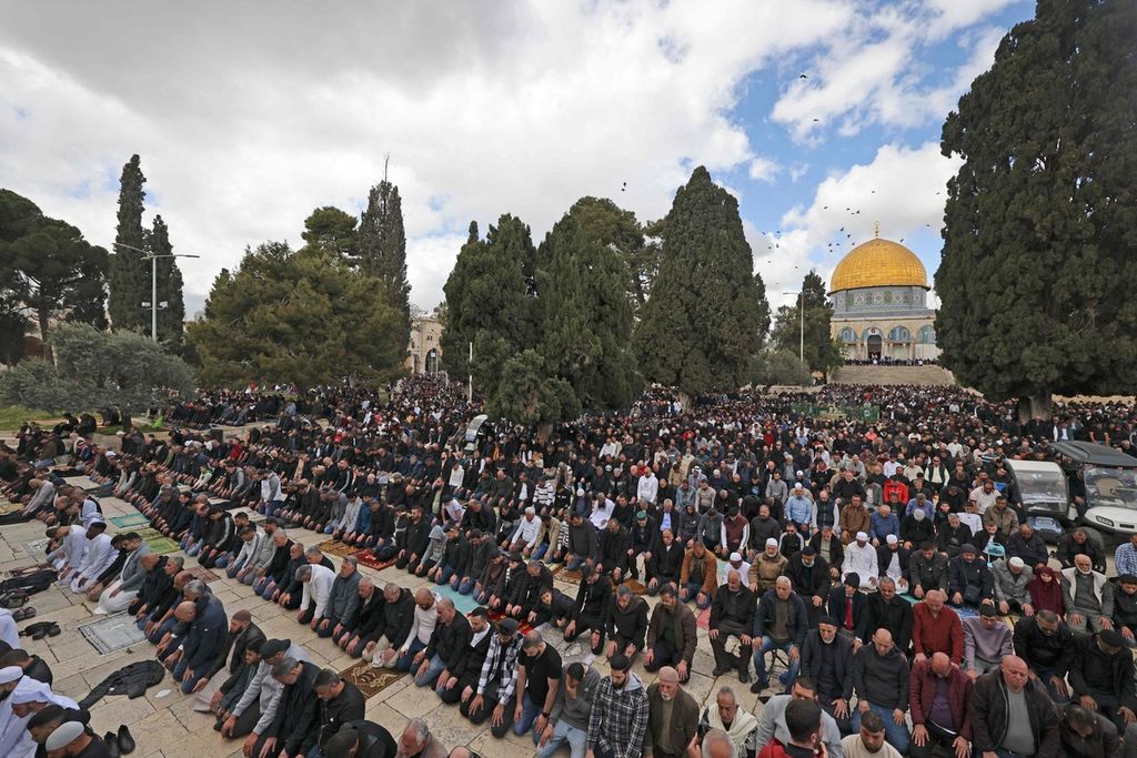 Warga Muslim menggelar shalat Jumat pertama pada bulan Ramadhan di kompleks Masjid Al-Aqsa, dengan pemandangan latar belakang bangunan Kubah Batu (Dome of the Rock) di Kota Tua Jerusalem Timur pada 15 Maret 2024. 