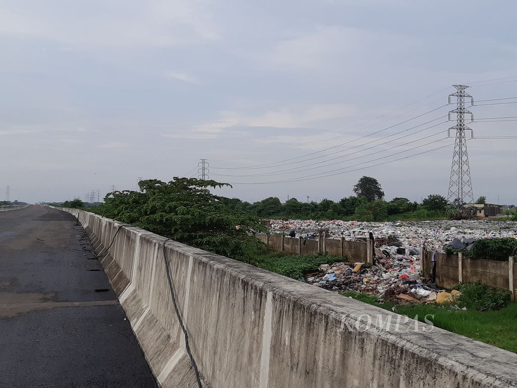 Kondisi tumpukan sampah yang diapit proyek Tol Cibitung Cilincing dan Kali Cikarang Bekasi Laut, di Desa Sumberjaya, Tambun Selatan, Kabupaten Bekasi, pada Selasa (25/1/2022) sore.