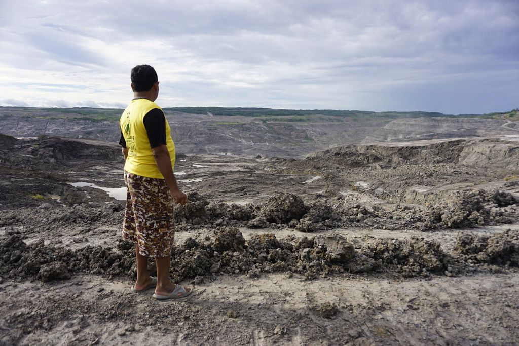 Suratno (54) melihat kegiatan tambang batubara yang berada sekitar 300 meter dari rumahnya di Desa Mulawarman, Kecamatan Tenggarong Seberang, Kutai Kartanegara, Kalimantan Timur, Minggu (5/1/2020).