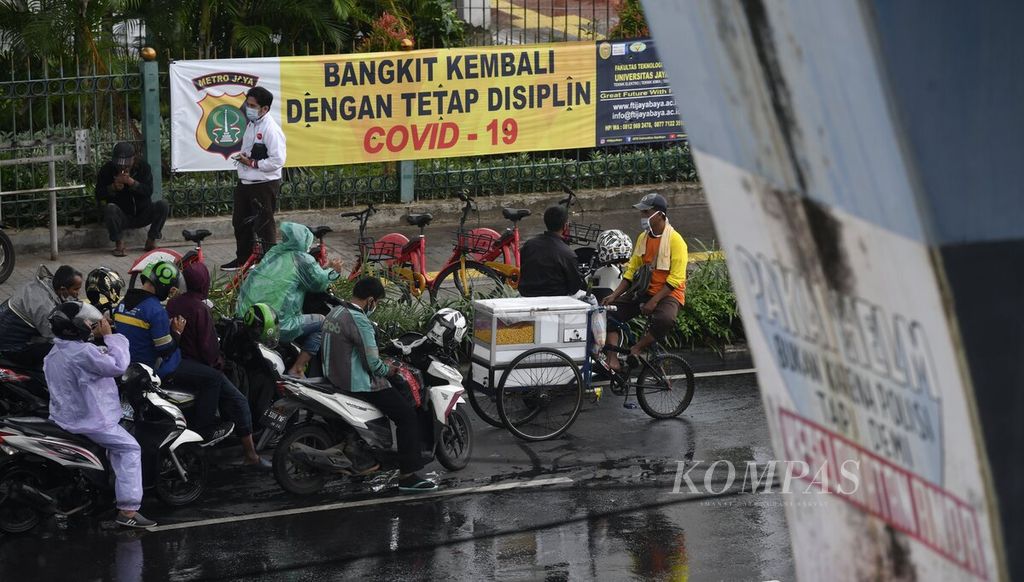 Sejumlah warga berteduh di bawah jembatan penyeberangan Stasiun Juanda, Jakarta, saat hujan turun, Selasa (18/1/2022). 