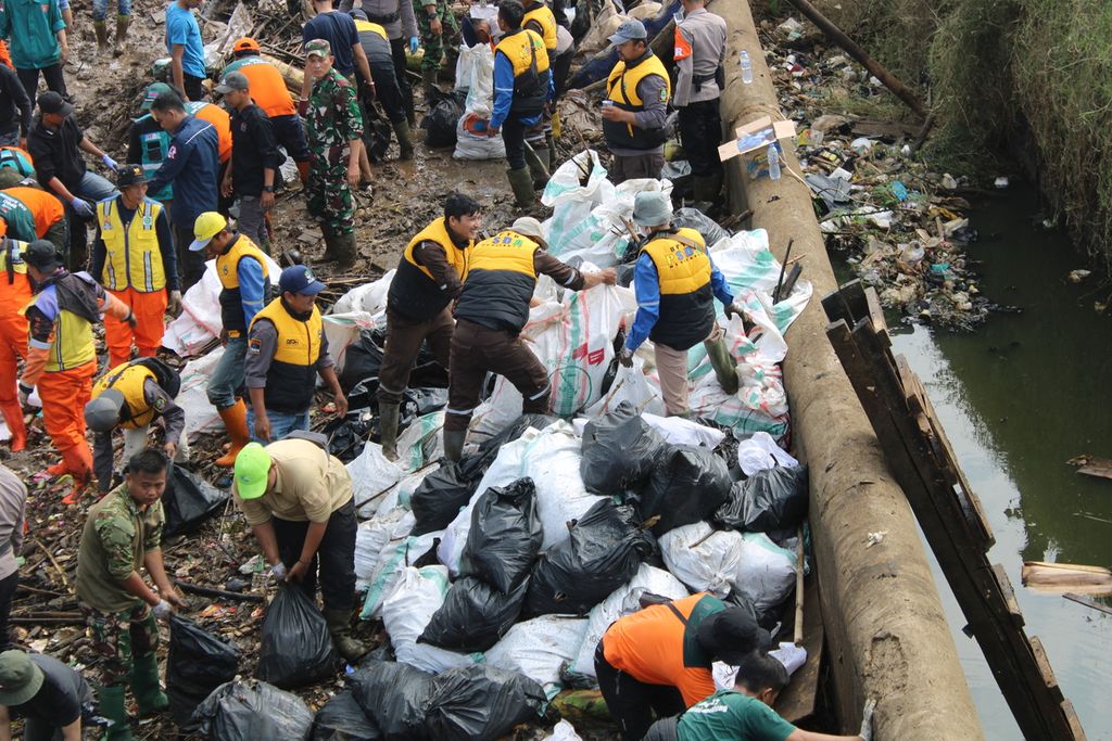 Petugas menumpuk karung sampah sebelum diangkut truk saat pembersihan badan Sungai Cikeruh di Bendungan Bugel, Kecamatan Cileunyi, Kabupaten Bandung, Jawa Barat, Rabu (26/7/2023). Dalam kegiatan yang diinisiasi Pandawara Group ini, dikumpulkan lebih dari 10 ton truk sampah.