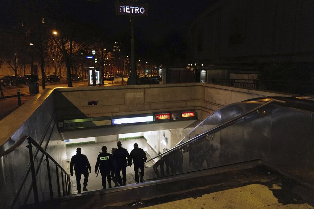 Sejumlah petugas dari kepolisian Perancis memasuki stasiun metro di Trocadero, dekat Menara Eiffel, saat berpatroli mengawasi pemberlakuan jam malam, di Paris, Perancis, Selasa (15/12/2020).  