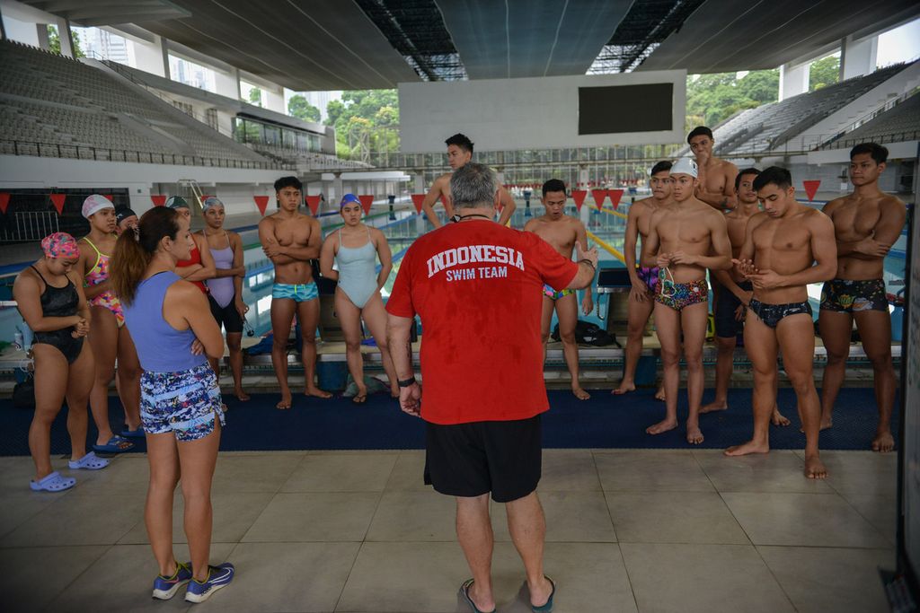 Pelatih tim renang Indonesia, Michael Piper (tengah, tampak belakang), memberikan instruksi kepada anak didiknya di Arena Akuatik Senayan, Jakarta, Senin (10/4/2023). Beberapa pekan menjelang SEA Games 2023, para atlet renang Indonesia terus berlatih demi mendapatkan hasil yang terbaik. Jadwal latihan para atlet tidak berkurang walaupun sejumlah atlet renang harus berpuasa di bulan Ramadhan. Agar fit, beberapa perenang meminum sejumlah vitamin saat sahur. Beberapa atlet renang juga harus berlapang dada merayakan Idul Fitri di tempat pemusatan latihan nasional atau pelatnas.