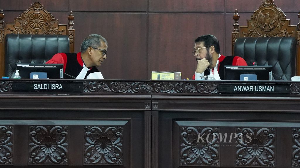 Ketua Mahkamah Konstitusi Anwar Usman (kanan) dan hakim MK Saldi Isra (kiri) berdiskusi sejenak disela-sela sidang putusan uji materiil Pasal 169 huruf q UU Pemilu terkait batas usia minimal calon presiden (capres) dan calon wakil presiden (cawapres) di Mahkamah Konstitusi, Jakarta, Senin (16/10/2023). 