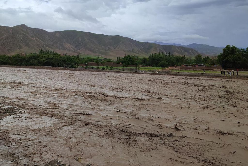 Penduduk Afghanistan berdiri di sebelah sungai yang penuh lumpur setelah banjir bandang melanda Distrik Nahrin, Provinsi Baghlan, Afghanistan, 10 Mei 2024. 