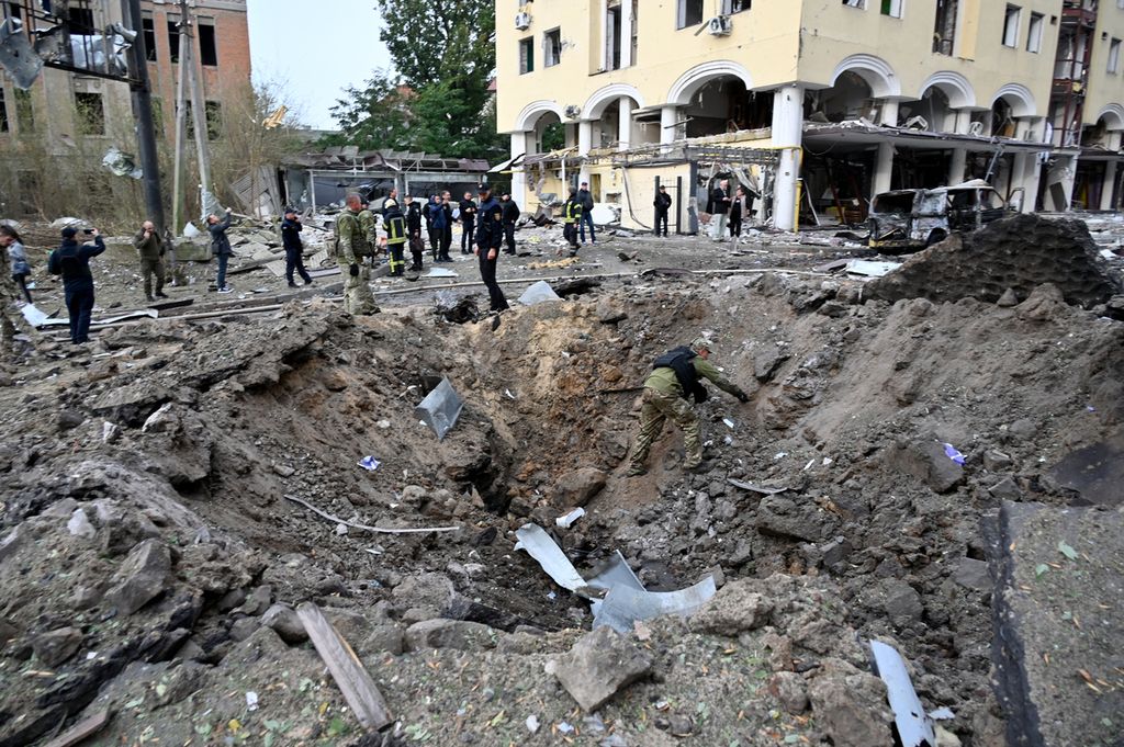 Seorang pakar memeriksa lubang setelah serangan Rusia ke pusat kota Kharkiv, di Rusia, pada 6 Oktober 2023, di tengah invasi Rusia ke Ukraina. Dalam serangan itu, setidaknya 16 orang terluka dan seorang anak dilaporkan tewas. 