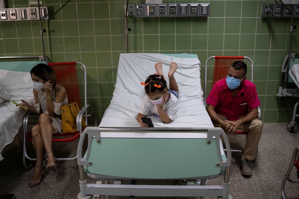 Seorang gadis bermain dengan ponselnya saat menunggu di ruang observasi setelah menerima suntikan vaksin Covid-19 menggunakan vaksin Cuban Soberana-02 di Havana, Kuba, Selasa (24/8/2021).